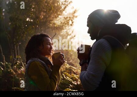 Happy young hiking couple drinking coffee in sunny woods Stock Photo