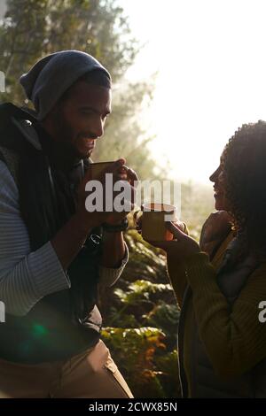 Happy young hiker couple drinking coffee in sunny woods Stock Photo