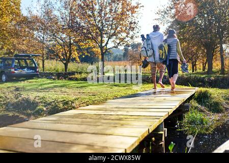 Barefoot young couple walking on sunny autumn lakeside dock Stock Photo