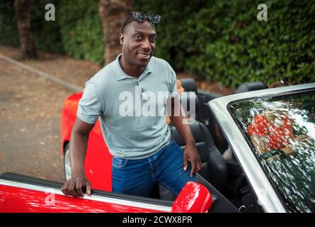Portrait handsome man getting into convertible Stock Photo