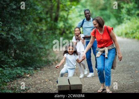 Happy family walking on trail in woods Stock Photo
