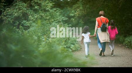 Mother and daughters hiking on path in woods Stock Photo