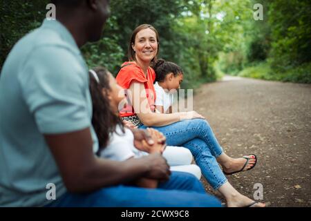 Happy family sitting on bench on path in park Stock Photo