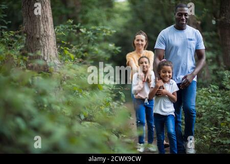 Happy family hiking on trail in woods Stock Photo