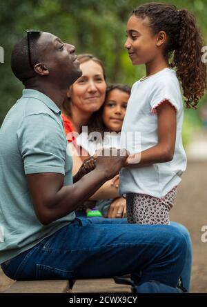 Happy family talking on park bench Stock Photo
