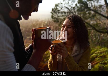 Happy young couple drinking coffee in sunny woods Stock Photo