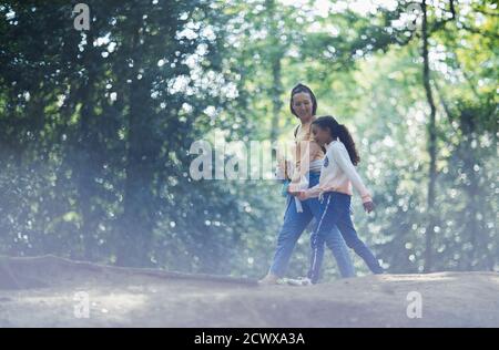 Mother and daughter holding hands hiking in summer woods Stock Photo