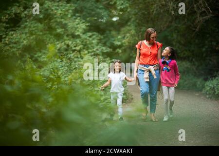 Mother and daughters walking on path in woods Stock Photo