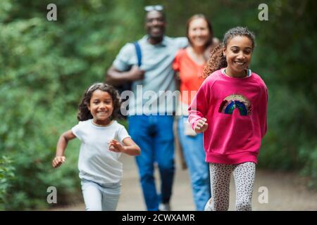 Happy family running and walking on path in woods Stock Photo