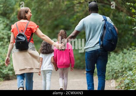 Affectionate family holding hands hiking on trail in woods Stock Photo