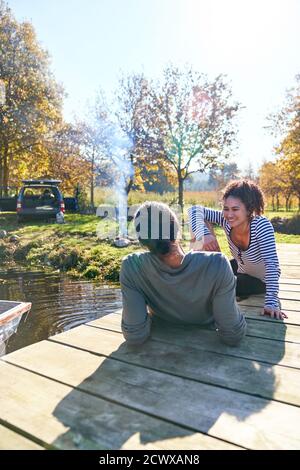 Happy young couple relaxing on sunny autumn dock near campsite Stock Photo