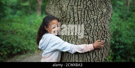 Serene girl hugging tree trunk in woods Stock Photo