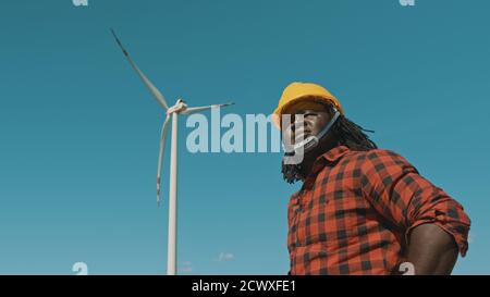 Young engineer african man with yellow helmet working in wind turbine farm . High quality photo Stock Photo