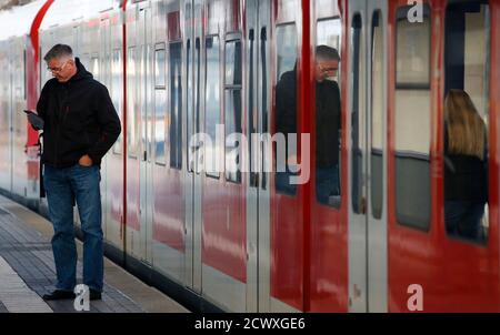 A passenger uses his mobile device to check for available commuter trains, while standing next to a closed regional train of German railway Deutsche Bahn at the train station in Hanau November 6, 2014. Germany is set for days of transport chaos after train drivers' union GDL called a strike from Wednesday over pay and negotiating rights, threatening to disrupt this weekend's celebrations of the 25th anniversary of the fall of the Berlin Wall.   REUTERS/ Kai Pfaffenbach (GERMANY - Tags: BUSINESS EMPLOYMENT CIVIL UNREST TRANSPORT)