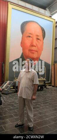 Ge Xiaoguang stands in front of a giant portrait of China's late Chairman Mao Zedong during a interview with Reuters in his working studio located between the Tiananmen Square and the Forbidden City in Beijing, June 29, 2011. Reclusive Chinese painter Ge's art has gazed over one of the world's most famous city squares for decades. For 30 years, he has painted the portraits of former paramount leader Mao Zedong that look across Beijing's Tiananmen Square. The giant oil paintings of the 'Great Helmsman' have kept watch from the Gate of Heavenly Peace since the Communist Party won the civil war a