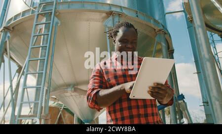 African farmer using laptop in front of the silo storage system. High quality photo Stock Photo