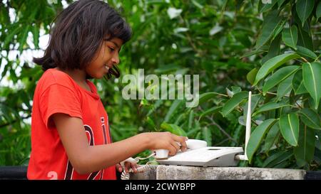 A little Indian girl using telephone. child playing telephone outdoor Stock Photo