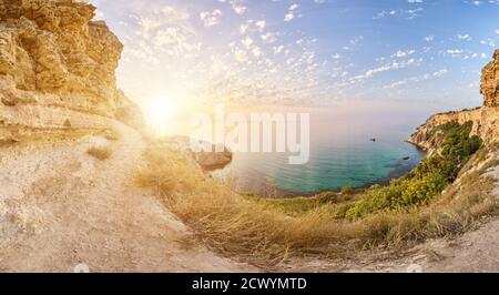 panorama on sunset time with beautiful clouds in the rocky bay with crystal clear azure sea on a sunny day. The concept of an ideal place for summer Stock Photo