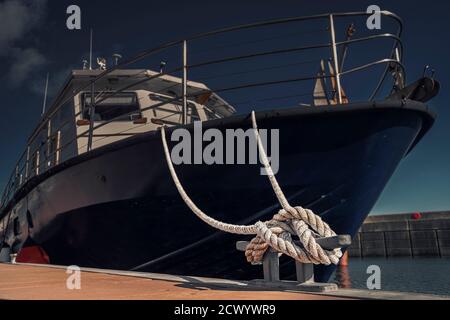 Close up of the mooring cleat with a boat rope tied around it. Connection visual concept as boat tied and linked to the pontoon. Stock Photo