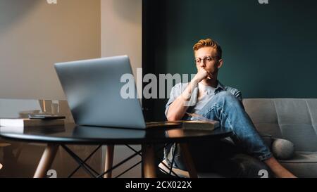 Pensive man college student in glasses studying with books laptop distantly Stock Photo