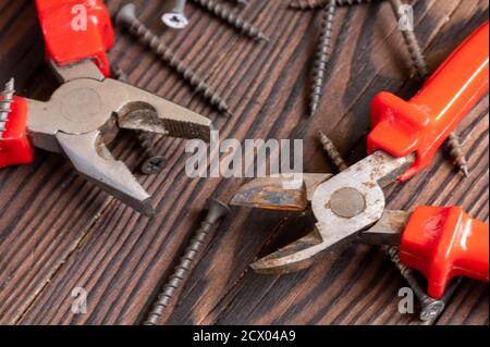 Pliers, side cutters, self-tapping screws on a wooden background, close-up, selective focus Stock Photo