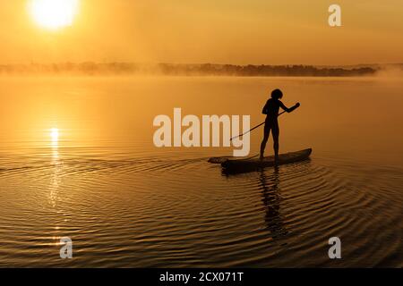 Active man using paddle for swimming on sup board Stock Photo