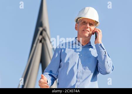 Architect or engineer talking on smart phone in front of technical construction - focus on the face Stock Photo
