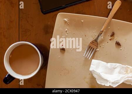 A flat lay image of a kitchen table after a quick breakfast on a workday. A cup of coffee, a smudged porcelain plate with olive stones, crumbles a use Stock Photo