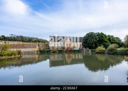 The large tithe barn and pond at the ruins of Abbotsbury Abbey, a former Benedictine monastery in Abbotsbury, Devon, south-east England Stock Photo