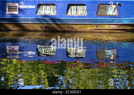 Abstract shapes created by the reflections of brightly painted narrow boat in water
