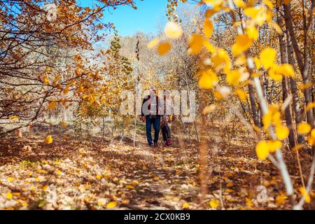 Fall season walk. Senior family couple walking in autumn park. Man and woman relaxing outdoors enjoying landscape Stock Photo