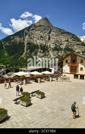 Elevated view of Abbé Henry square in the centre of the famous mountain town with tourists and the Mont Chetif peak in summer, Courmayeur, Italy Stock Photo