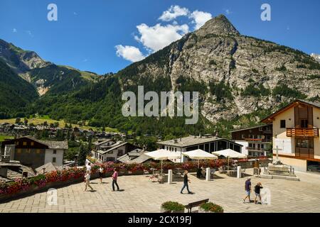 Elevated view of Abbé Henry square in the centre of the famous mountain town with tourists and the Mont Chetif peak in summer, Courmayeur, Italy Stock Photo