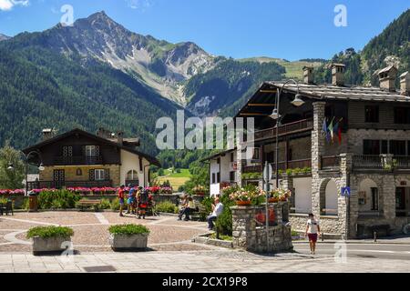 View of Brocherel square in the centre of the famous mountain town with people and backpackers in summer, Courmayeur, Aosta Valley, Italy Stock Photo