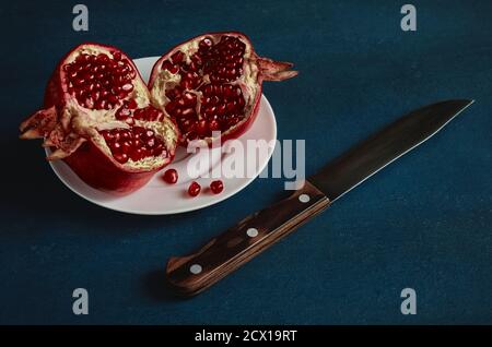 Ripe fruit pomegranate and knife on dark background, vintage stylization Stock Photo