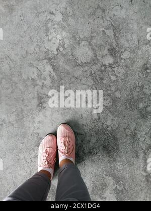 top view old brown tone leather shoe detail on grunge concrete floor, Selfie feet wearing sneakers shoes on floor. Stock Photo