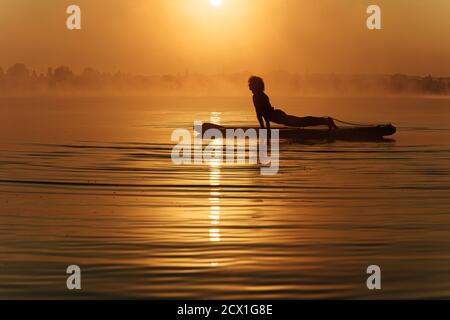 Young man doing plank exercise on paddle board Stock Photo