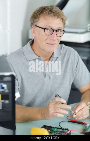 man repairing a computer using a multimeter Stock Photo