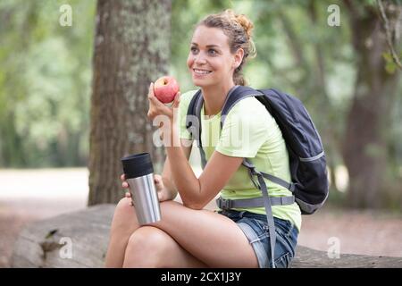 woman hiker resting and eating an apple sitting Stock Photo