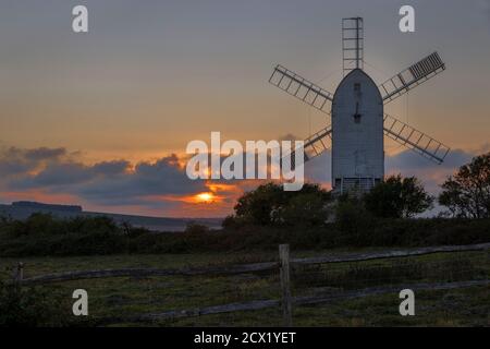 Watching the sun go down behind Ashcombe mill and the south downs on the Kingston Ridge near Lewes in east Sussex south east England Stock Photo