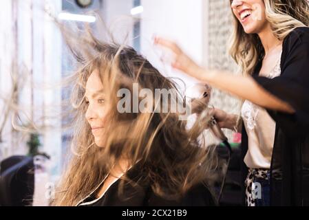 Hairdresser combing a client with the dryer in a hairdresser's shop Stock Photo