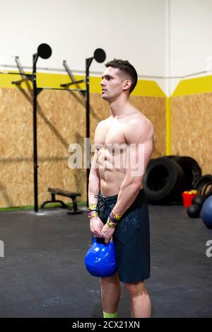 Strong man with dumbbell in hands doing strength exercises in the gym Stock Photo
