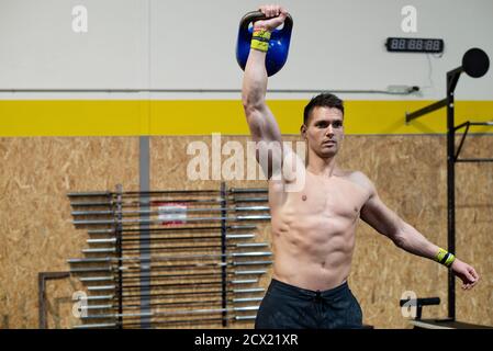 Strong man with dumbbell in his hand doing strength exercises in the gym Stock Photo
