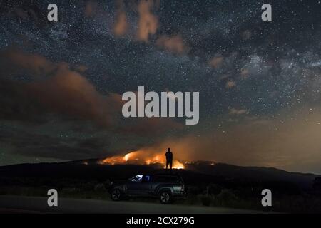 Man looking at wildfire while standing on off-road vehicle against star field Stock Photo