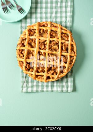 Top view with a home-baked apple pie on a green table. Apple tart with a green kitchen towel under it. Homemade cake with apple filling and lattice cr Stock Photo