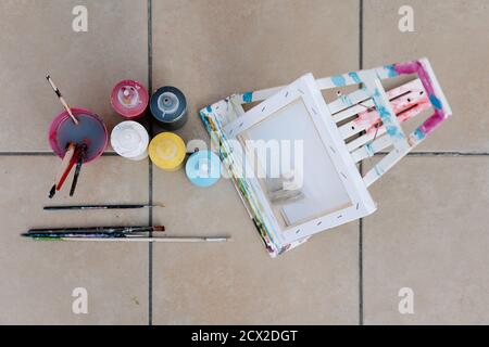 painting bottles, brushes, easel and picture on the floor of a terrace. Overhead horizontal photo Stock Photo
