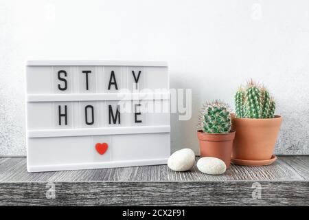 Lightbox with text STAY HOME and cactus plants on wooden table. Stay safe, stay inside home concept - Image Stock Photo