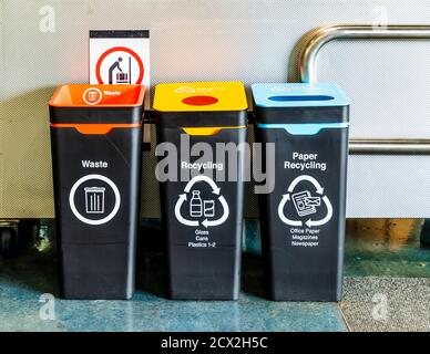 Auckland, New Zealand: Recycling bins for Waste (red lid), Glas, Cans, Plastic (yellow lid) and Paper Recycling (blue lid) at Auckland Intern. Airport Stock Photo