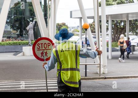 Auckland, New Zealand: Crossing guard with Stop sign at a zebra crossing in front of the terminal of Auckland International Airport Stock Photo