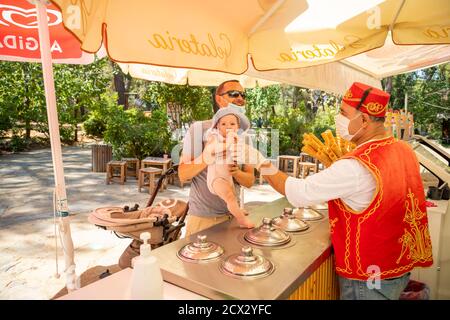 Antalya, Turkey - 4.09.2020: Seller give Traditional turkish ice cream to man with baby girl in a summer day in Antalya, Turkey Stock Photo